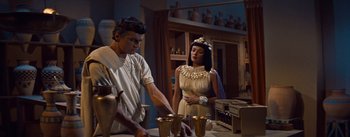 Movie still from “The Egyptian” (1954), directed by Michael Curtiz – A woman standing next to a man in a costume; Medium shot, Low angle