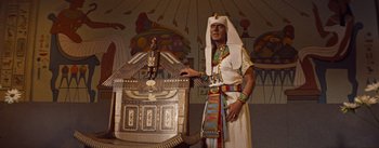 Movie still from “The Egyptian” (1954), directed by Michael Curtiz – A man dressed as a pharaoh standing next to an egyptian statue; Medium shot, Low angle