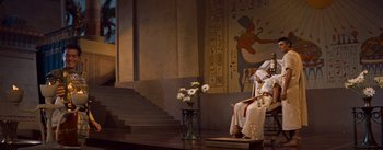 Movie still from “The Egyptian” (1954), directed by Michael Curtiz – A vase of flowers sitting on the ground in front of stairs; Extreme Wide shot, Low angle