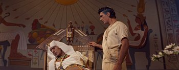 Movie still from “The Egyptian” (1954), directed by Michael Curtiz – A man standing next to an older man in egyptian clothing; Medium shot, Overhead angle