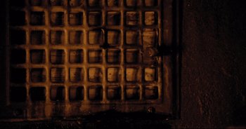 Movie still from “The Element of Crime” (1984), directed by Lars von Trier – A grate in the dark; Extreme Close Up shot, Overhead angle