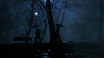 Movie still from “The End of the Affair” (1999), directed by Neil Jordan – Two people walking in the rain with umbrellas; Wide shot, High angle
