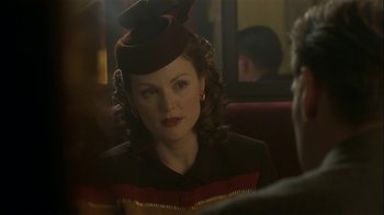 Movie still from “The End of the Affair” (1999), directed by Neil Jordan – A woman in a hat sitting in a chair; Close Up shot, Over the shoulder angle