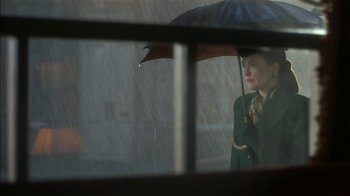 Movie still from “The End of the Affair” (1999), directed by Neil Jordan – A woman holding an umbrella while standing in the rain; Close Up shot, Over the shoulder angle