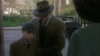 Movie still from “The End of the Affair” (1999), directed by Neil Jordan – A man and a young boy wearing suits and hats; Medium shot, Over the shoulder angle