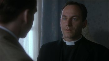 Movie still from “The End of the Affair” (1999), directed by Neil Jordan – A man wearing a priest's outfit talking to another man; Close Up shot, Low angle