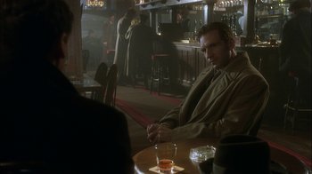 Movie still from “The End of the Affair” (1999), directed by Neil Jordan – A man sitting at a table in front of a glass of beer; Medium shot, Over the shoulder angle