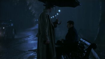 Movie still from “The End of the Affair” (1999), directed by Neil Jordan – Two men sitting under an umbrella on a bench at night; Medium shot, Over the shoulder angle
