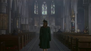 Movie still from “The End of the Affair” (1999), directed by Neil Jordan – A woman in a green dress standing in a church; Wide shot, Low angle