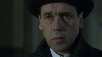 Movie still from “The End of the Affair” (1999), directed by Neil Jordan – A person wearing a suit and hat; Close Up shot, Over the shoulder angle