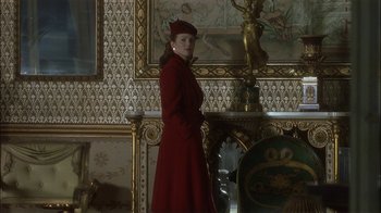 Movie still from “The End of the Affair” (1999), directed by Neil Jordan – A woman in a red coat standing in front of a fireplace; Medium shot, Low angle