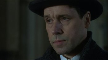 Movie still from “The End of the Affair” (1999), directed by Neil Jordan – A person wearing a suit and hat; Close Up shot, Over the shoulder angle