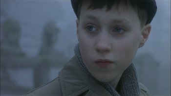 Movie still from “The End of the Affair” (1999), directed by Neil Jordan – A young boy wearing a hat and a jacket; Close Up shot, High angle