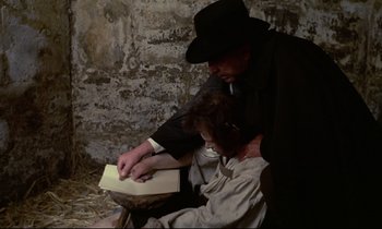 Movie still from “The Enigma of Kaspar Hauser” (1974), directed by Werner Herzog – A man and a woman sitting on the ground reading a book; Medium shot, High angle