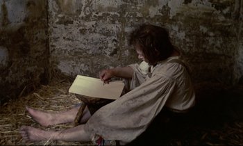 Movie still from “The Enigma of Kaspar Hauser” (1974), directed by Werner Herzog – A man sitting on a chair in a barn; Medium shot, High angle
