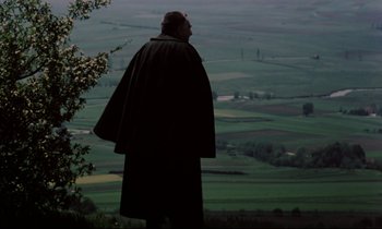 Movie still from “The Enigma of Kaspar Hauser” (1974), directed by Werner Herzog – A man standing on top of a hill looking out at a valley; Medium shot, Over the shoulder angle