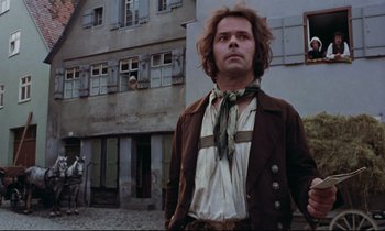 Movie still from “The Enigma of Kaspar Hauser” (1974), directed by Werner Herzog – A man standing in front of an old building; Medium shot, Low angle