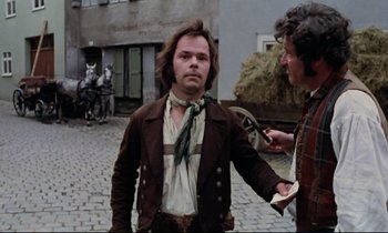 Movie still from “The Enigma of Kaspar Hauser” (1974), directed by Werner Herzog – A man in a brown jacket and a green neck tie; Medium shot, Over the shoulder angle