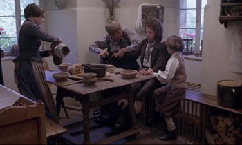 Movie still from “The Enigma of Kaspar Hauser” (1974), directed by Werner Herzog – A group of people sitting around a table with bowls on top of it; Wide shot, High angle