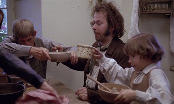 Movie still from “The Enigma of Kaspar Hauser” (1974), directed by Werner Herzog – A group of people sitting at a table eating food; Medium shot, Low angle