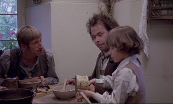 Movie still from “The Enigma of Kaspar Hauser” (1974), directed by Werner Herzog – Three people sitting at a table with a bowl of food; Medium shot, Over the shoulder angle