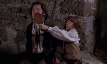 Movie still from “The Enigma of Kaspar Hauser” (1974), directed by Werner Herzog – A young boy is brushing a young man's hair with a brush; Medium shot, Over the shoulder angle