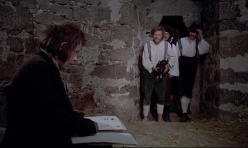 Movie still from “The Enigma of Kaspar Hauser” (1974), directed by Werner Herzog – A group of people standing in a room; Medium shot, Over the shoulder angle