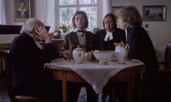 Movie still from “The Enigma of Kaspar Hauser” (1974), directed by Werner Herzog – A group of people sitting around a table; Medium shot, Over the shoulder angle