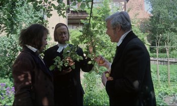 Movie still from “The Enigma of Kaspar Hauser” (1974), directed by Werner Herzog – Two women and an older man are standing under a tree; Medium shot, Over the shoulder angle