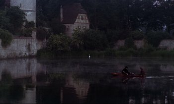 Movie still from “The Enigma of Kaspar Hauser” (1974), directed by Werner Herzog – A person in a boat on a body of water at night; Extreme Wide shot, High angle