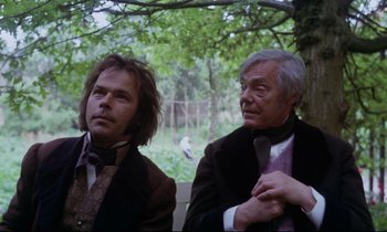 Movie still from “The Enigma of Kaspar Hauser” (1974), directed by Werner Herzog – Two men sitting next to each other in front of a tree; Medium shot, Over the shoulder angle