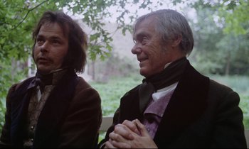 Movie still from “The Enigma of Kaspar Hauser” (1974), directed by Werner Herzog – Two men are sitting next to each other in a park; Medium shot, Over the shoulder angle