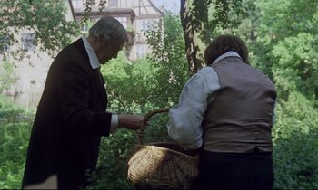 Movie still from “The Enigma of Kaspar Hauser” (1974), directed by Werner Herzog – A man and a woman holding a basket in a forest; Medium shot, Over the shoulder angle