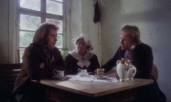 Movie still from “The Enigma of Kaspar Hauser” (1974), directed by Werner Herzog – A group of people sitting at a wooden table; Medium shot, High angle