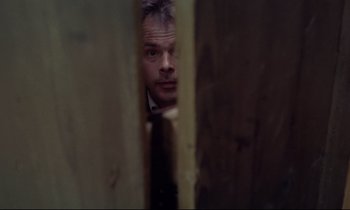 Movie still from “The Enigma of Kaspar Hauser” (1974), directed by Werner Herzog – A man in a suit peeks out from behind a wooden wall; Close Up shot, Low angle
