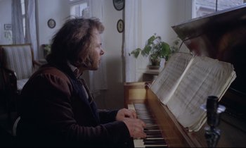 Movie still from “The Enigma of Kaspar Hauser” (1974), directed by Werner Herzog – A man sitting at a piano looking at a sheet of music; Medium shot, High angle