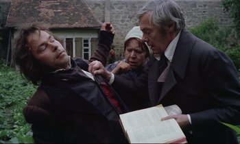 Movie still from “The Enigma of Kaspar Hauser” (1974), directed by Werner Herzog – An older man holding onto a tie while a younger man and woman look on; Medium shot, High angle