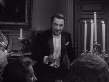 Movie still from “The Exterminating Angel” (1962), directed by Luis Buñuel – A black and white photo of a man in a tuxedo; Medium shot, Over the shoulder angle