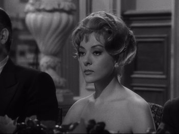 Movie still from “The Exterminating Angel” (1962), directed by Luis Buñuel – A black - and - white photo of a woman in a dress; Close Up shot, Over the shoulder angle