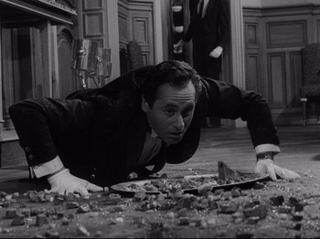 Movie still from “The Exterminating Angel” (1962), directed by Luis Buñuel – A black and white photo of a man laying on the ground; Medium shot, Overhead angle