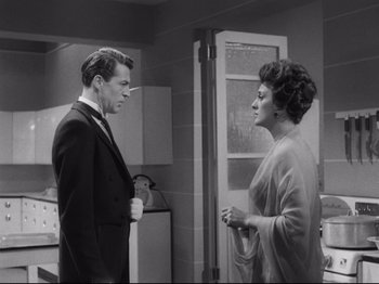 Movie still from “The Exterminating Angel” (1962), directed by Luis Buñuel – A man and a woman standing next to each other in a room; Medium shot, Over the shoulder angle