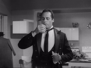 Movie still from “The Exterminating Angel” (1962), directed by Luis Buñuel – A black and white photo of a man drinking a glass of wine; Medium shot, Low angle