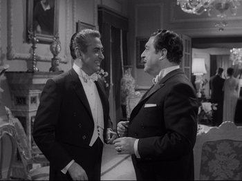 Movie still from “The Exterminating Angel” (1962), directed by Luis Buñuel – Two men in tuxedos talking to each other; Medium shot, Over the shoulder angle