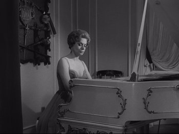 Movie still from “The Exterminating Angel” (1962), directed by Luis Buñuel – A black and white photo of a woman playing a piano; Medium shot, Low angle