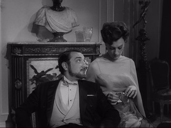 Movie still from “The Exterminating Angel” (1962), directed by Luis Buñuel – A man and a woman sitting next to each other in a room; Medium shot, Low angle