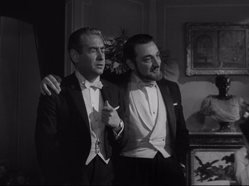 Movie still from “The Exterminating Angel” (1962), directed by Luis Buñuel – Two men in tuxedos posing for a picture; Medium shot, Low angle