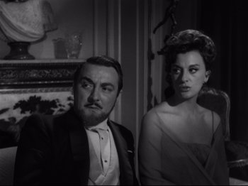 Movie still from “The Exterminating Angel” (1962), directed by Luis Buñuel – A man and a woman are sitting next to each other; Close Up shot, Over the shoulder angle