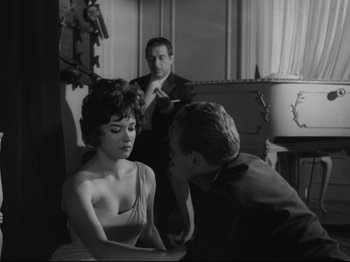 Movie still from “The Exterminating Angel” (1962), directed by Luis Buñuel – A man and a woman sitting next to each other in a room; Medium shot, Over the shoulder angle