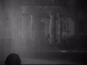 Movie still from “The Exterminating Angel” (1962), directed by Luis Buñuel – A black - and - white photo of a building in the pouring rain; Extreme Wide shot, Low angle