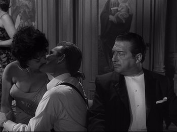 Movie still from “The Exterminating Angel” (1962), directed by Luis Buñuel – Two men and a woman in front of a painting; Medium shot, Over the shoulder angle